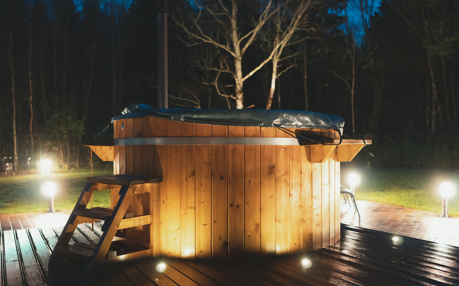 Wooden hot tub with fireplace at night.